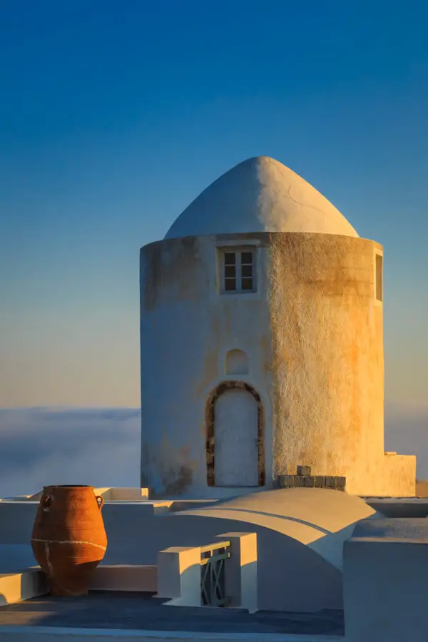 Windmill building and greek urn at sunrise on Santorini